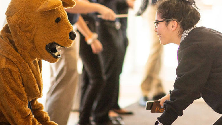 Student interacting with Nittany Lion mascot.