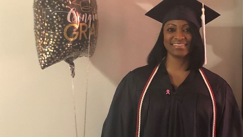 graduate in cap and gown holding balloons