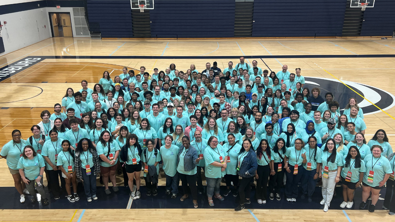 a large group of students smiling in a gymnasium 