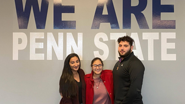 three students under We Are Penn State sign