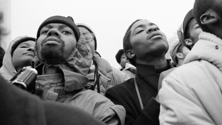 a black and white, close-up photograph of two men standing. 