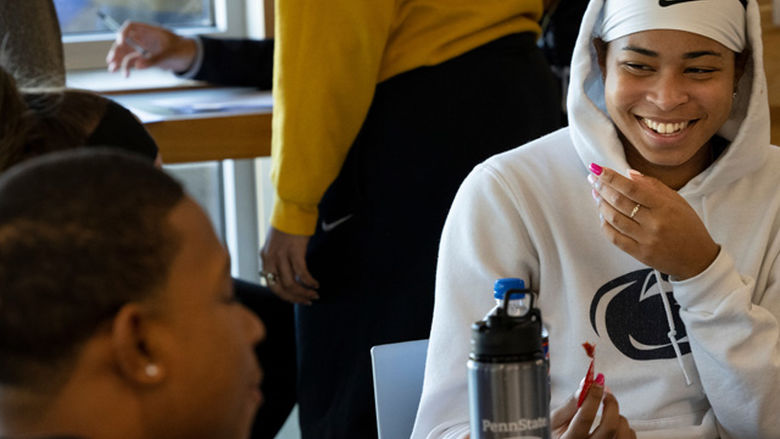 Student smiling and sitting at table with other student