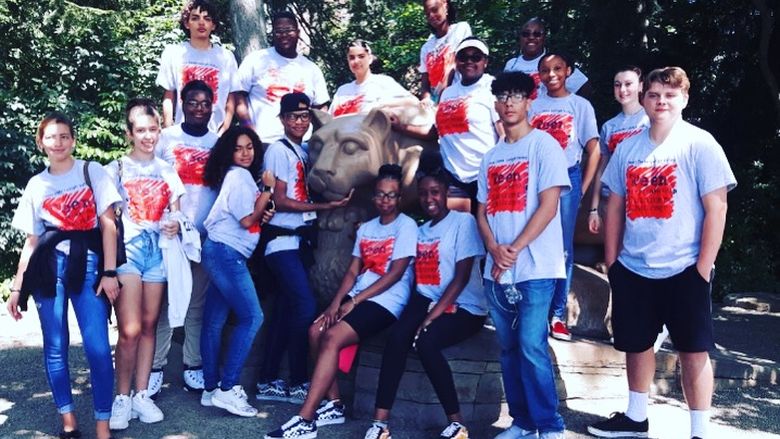 campers posing at lion shrine at university park