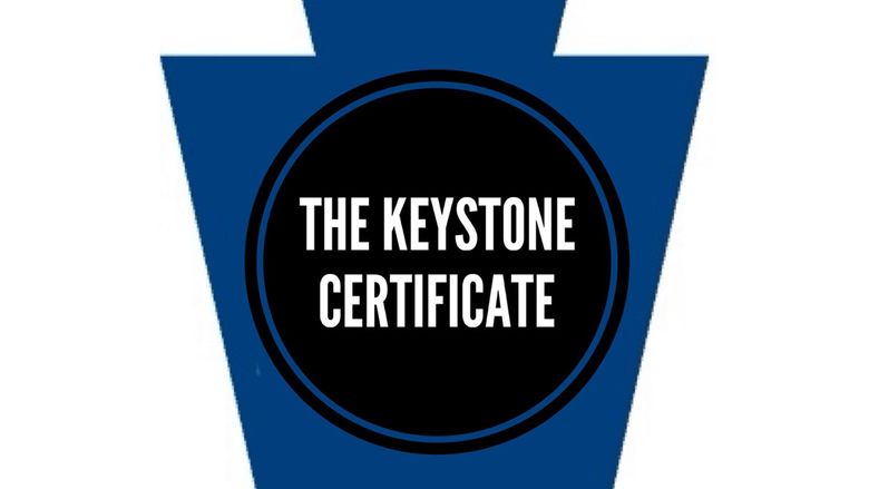 A dark blueKeystone shape with a black circle in the middle and the words "Keystone Certificate" inside the circle.