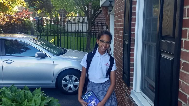 young girl in school uniform holding a book