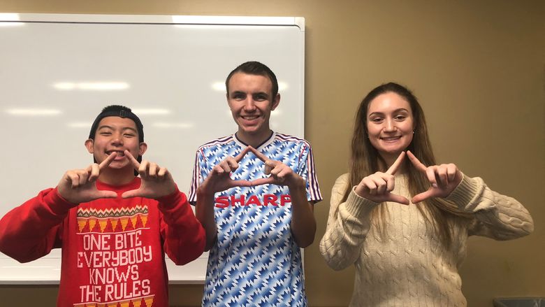 Three college students making THON diamond with hands