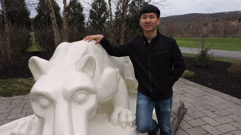 student standing next to nittany lion shrine