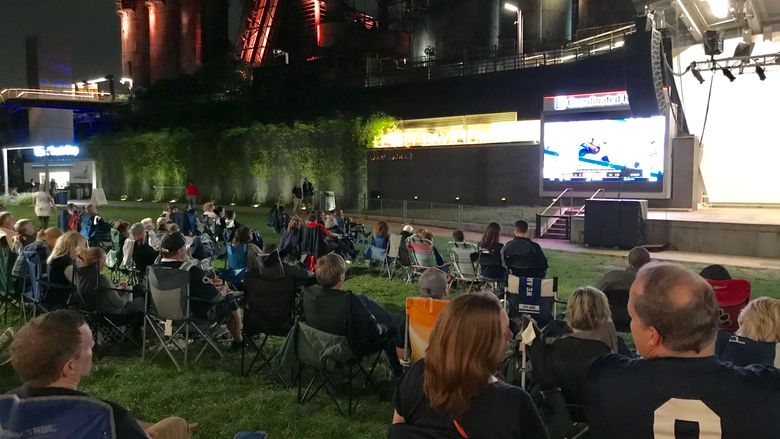 large group of people watching football game on big screen in front of Levitt Pavilion SteelStacks