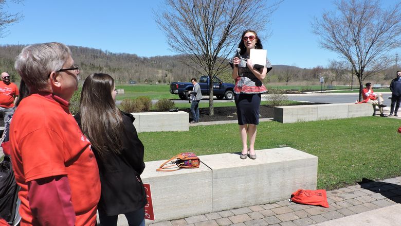 woman standing on bench speaking to group