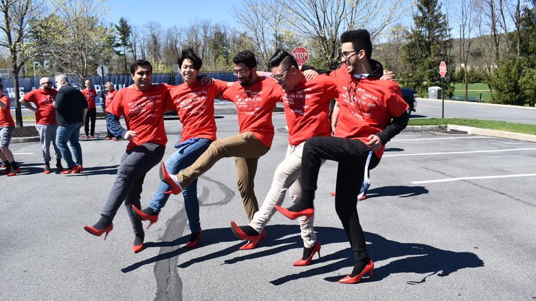 men kicking their legs wearing red heels and red shirts