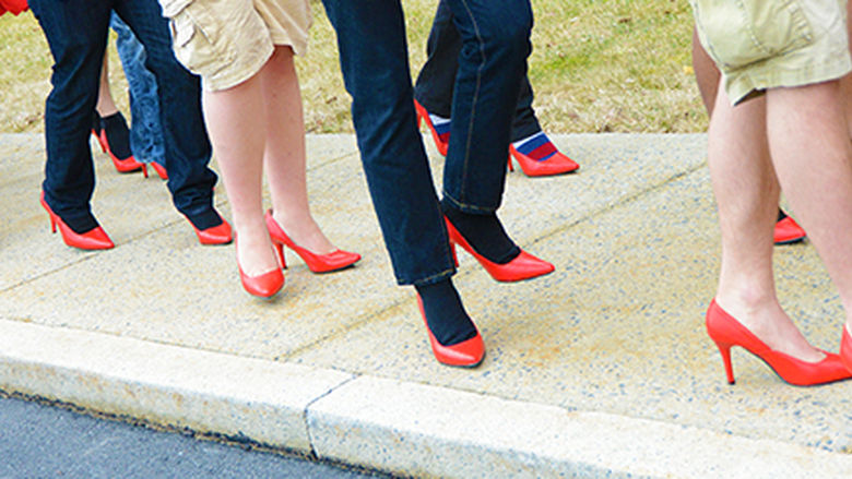 Men wearing red high heels walking around campus