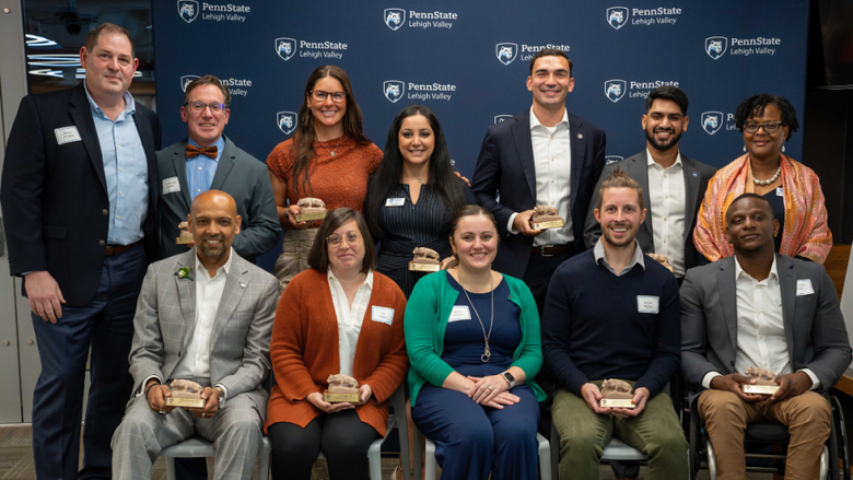 a group of Penn State Lehigh Valley award recipients smiling in front of a blue backdrop