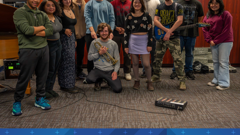 a group of students smile in a room full of instruments