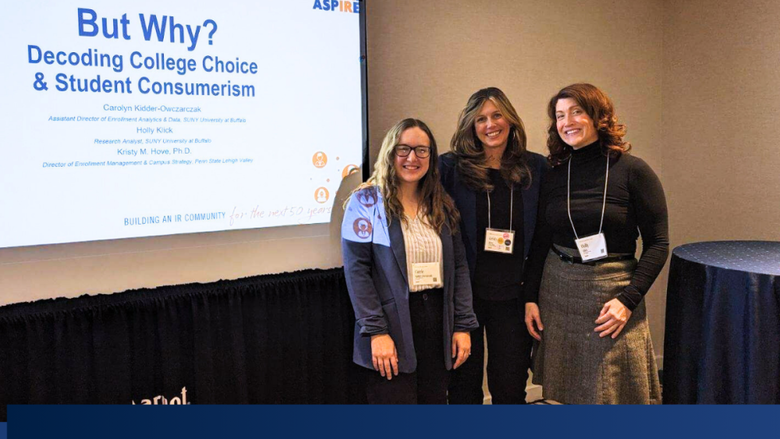 three people smile in front of a projector at a conference