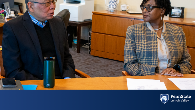 a male and female sit at a conference table speaking
