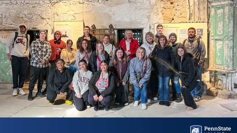 a group of students and teachers smile as a group while touring an old prison