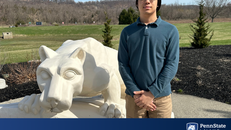 a male college student stands in front of the penn state lion shrine 