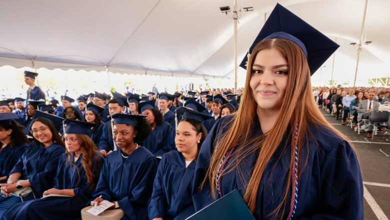 A woman in blue regalia smiles as she holds her blue Penn State Lehigh Valley diploma