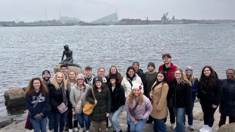 A group of students pose at a waterfront
