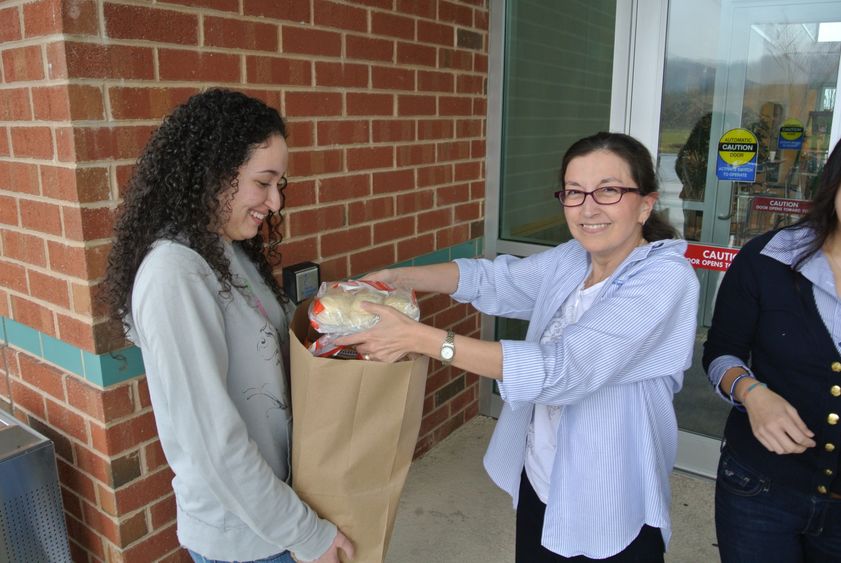 Faculty member and student packing a bag of food donations