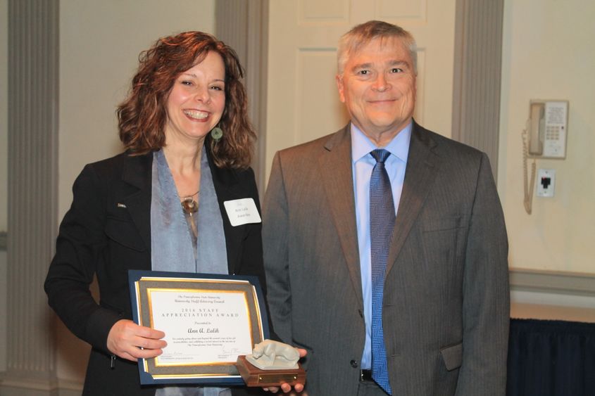 Two people stand with award