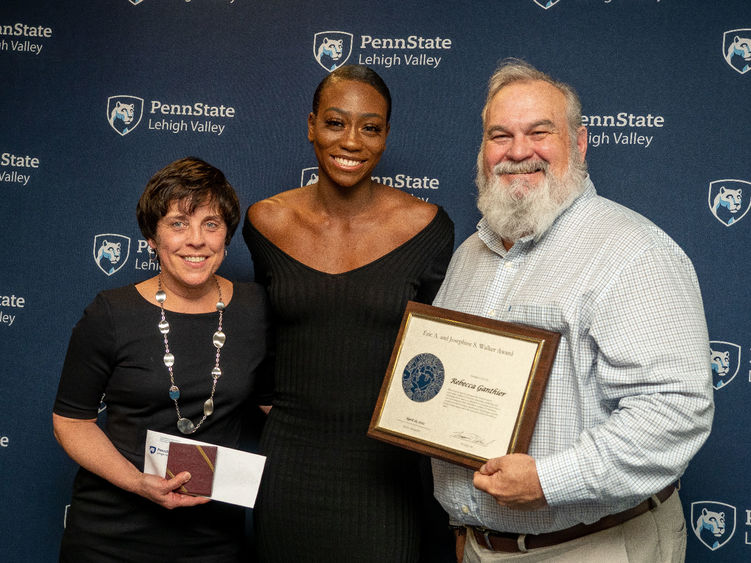 Student and staff pose for camera at awards ceremony 