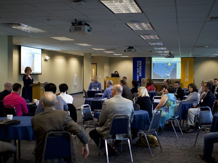 Susie Krajsa speaking at the podium to a full room