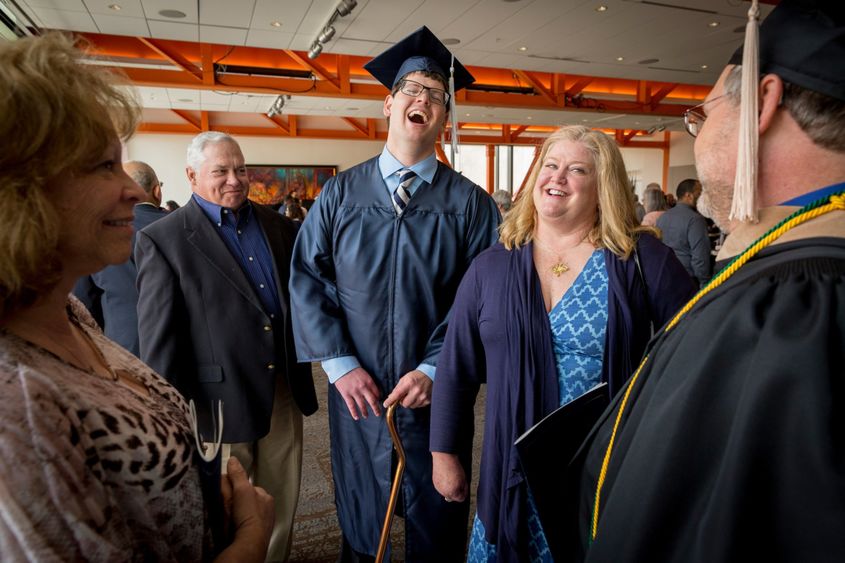 a graduate smiling with his parents