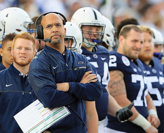 Coach Franklin standing on sidelines looking up with headset on