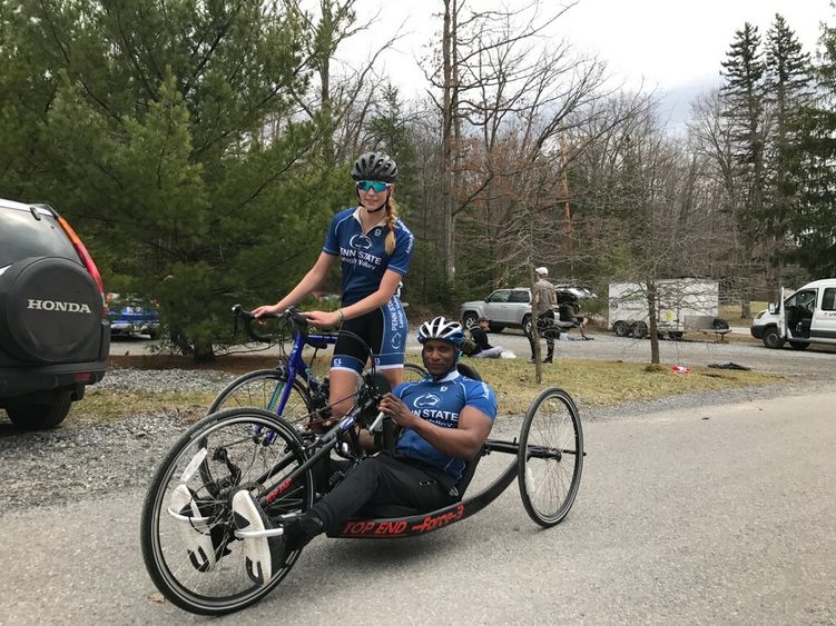 Two cyclists, one on a traditional bike, on using a hand cycle