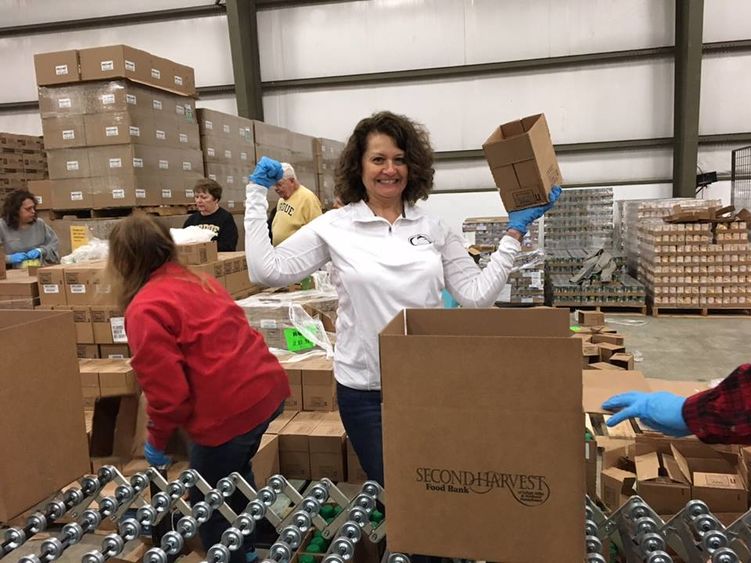 Diane McAloon holding food up whild packing donations
