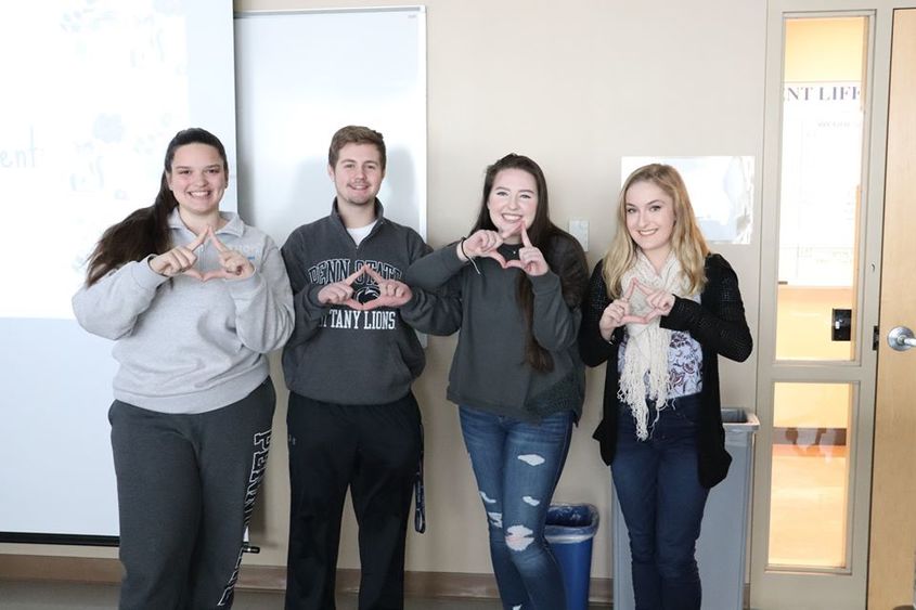 four college students making diamonds with their hands