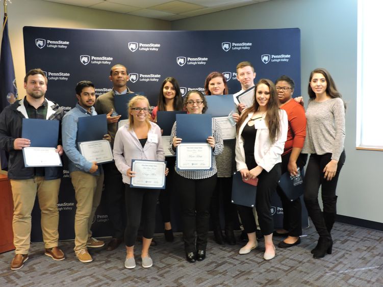 Group of student winners posed in front of step and repeat banner with Keynote speaker