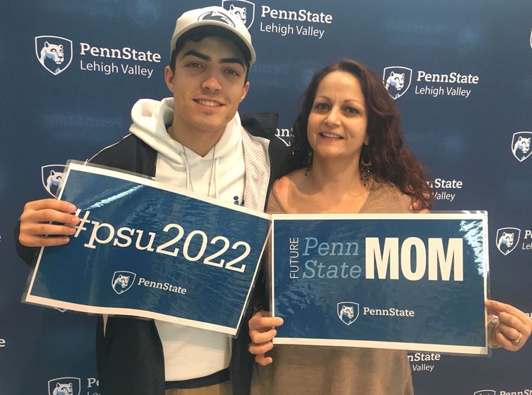Son and Mom holding PSU signs in front of step and repeat banner with PSU-LV logo repeating on it