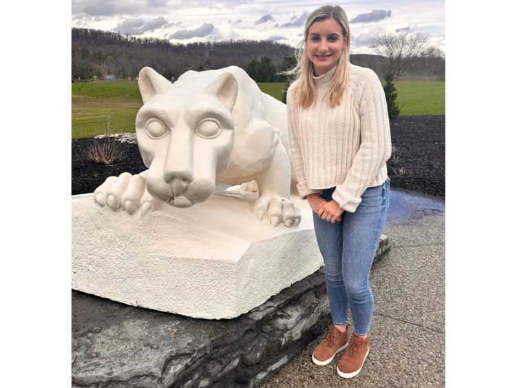 a female student standing in front of the lion shrine