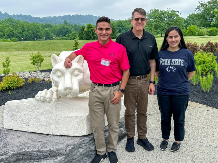 3 adults smile in front of a lion shrine