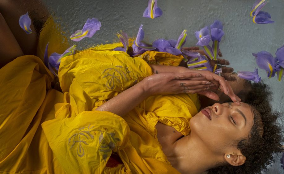 woman in yellow laying around purple flowers