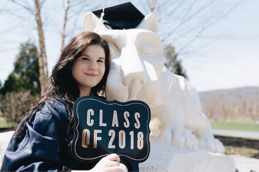 Student with cap and gown in front of lion shrine