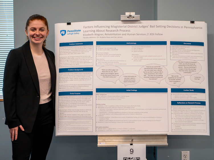 A student smiling next to a research poster