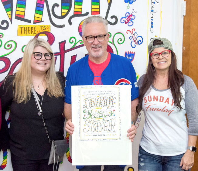 three people pose in front of a mural