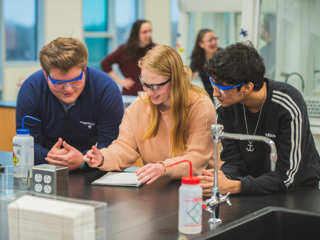 students examining a sample through a microscope