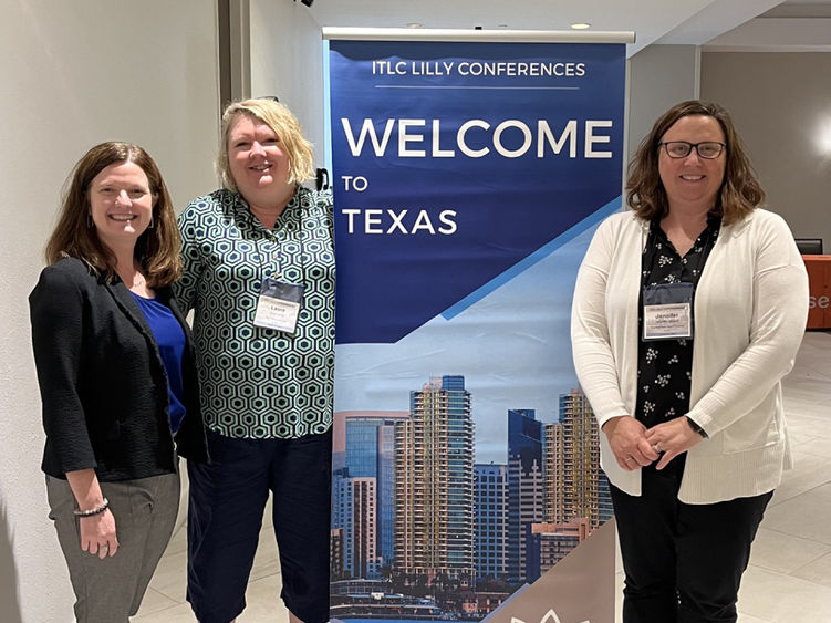 Three people pose next to a banner with text saying Welcome to Texas