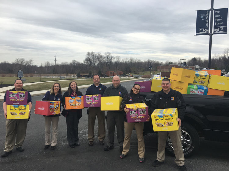 Group of volunteers holding donated food during food drive event