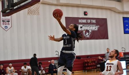 men's basketball player jumping up to the basket to score