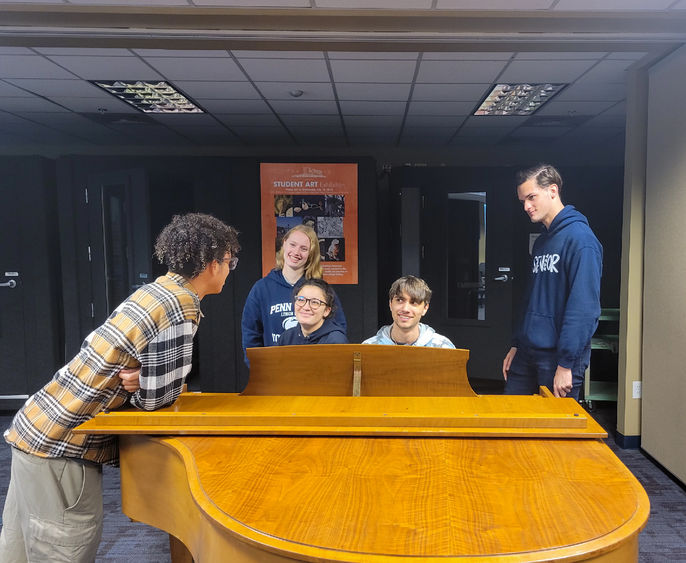 Penn State Lehigh Valley Students talking around the piano in campus music room