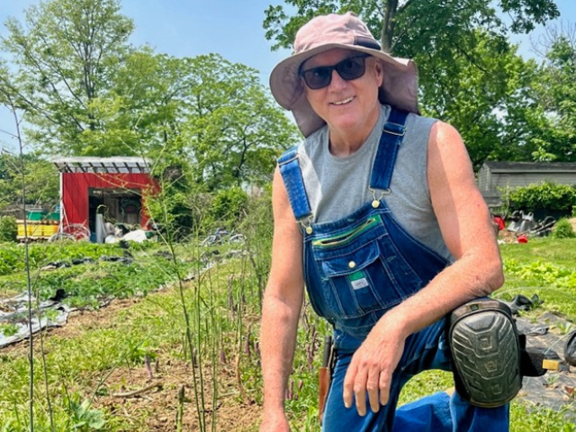 Professor Kevin Kelley smiling while kneeling in a garden