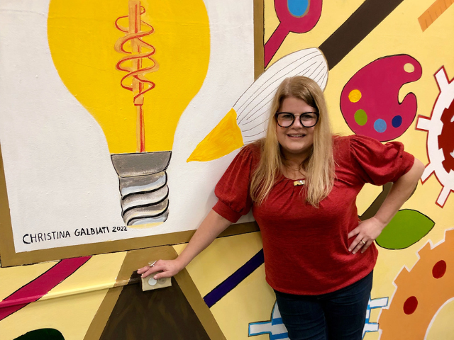 Christina Galbiati standing in front of STEAM-themed mural