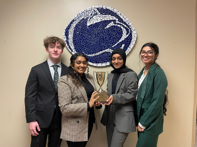 Students holding trophy in front of lion mosaic