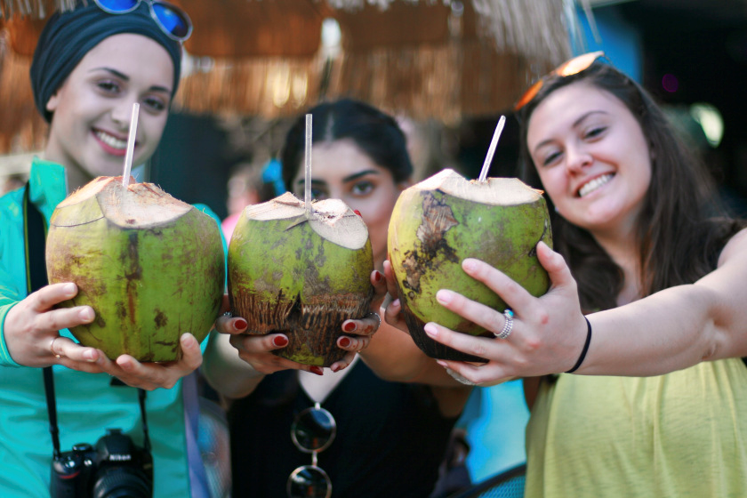 Three young women holding coconut drinks