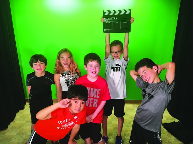 A group of kids pose in front of a Green screen